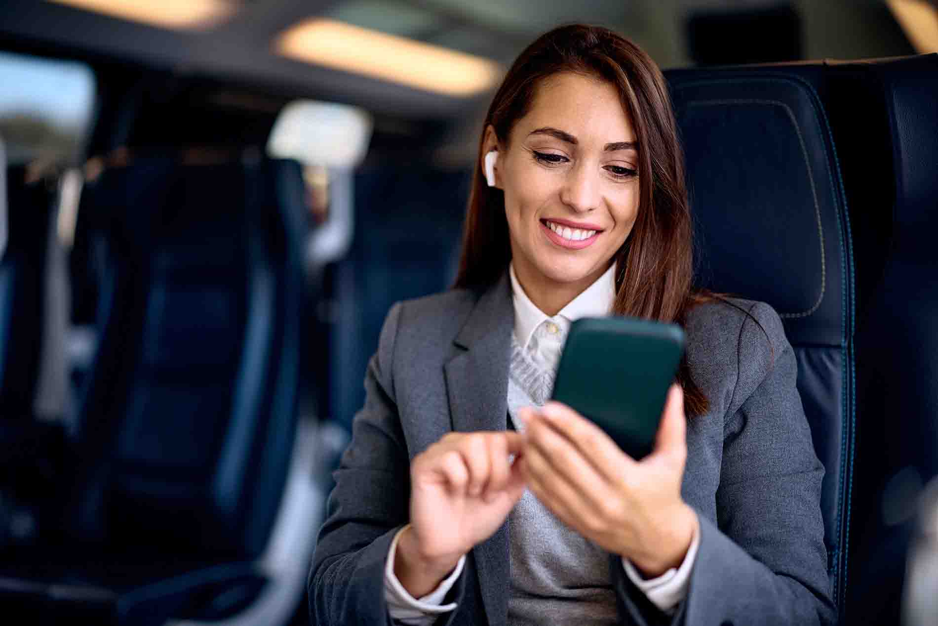 Young happy woman using smart phone while riding in a train. Copy space.