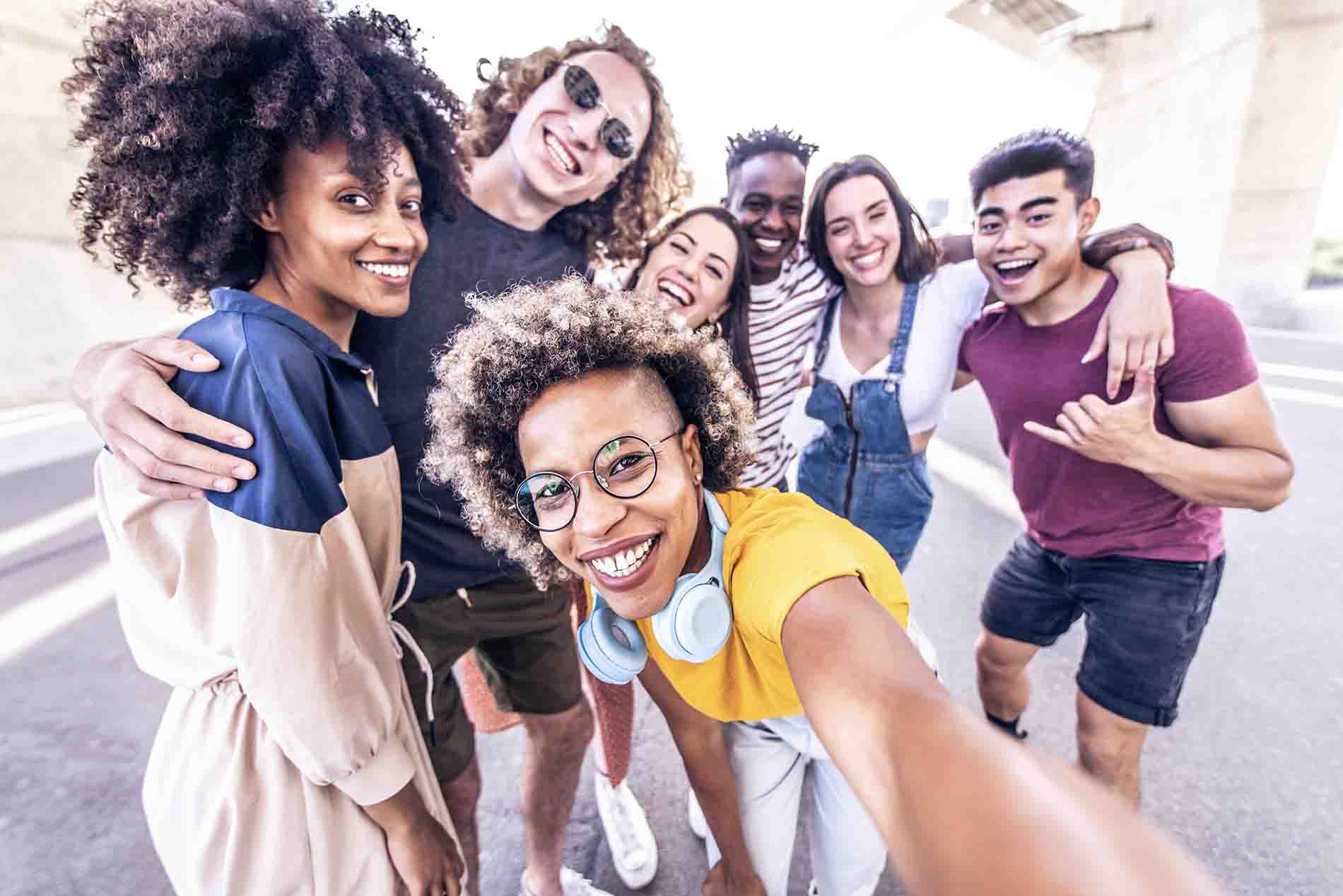 Multiracial friends taking selfie photo with smart mobile phone outside - Group of young people smiling together at camera - Friendship concept with guys and girls having fun on city street