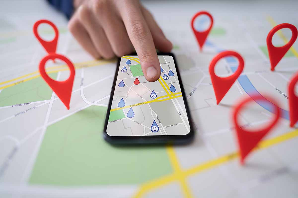 Person Using Map With Red Location Markers On Mobile Phone